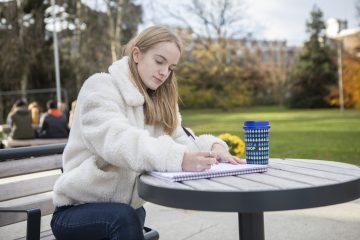 A photo of a student with a reusable coffee cup